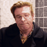 a man wearing glasses and a plaid shirt is looking down