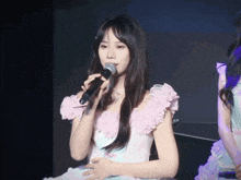 a girl in a pink dress holds a microphone