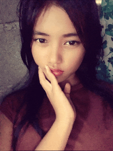 a close up of a girl 's face with her hand on her chin