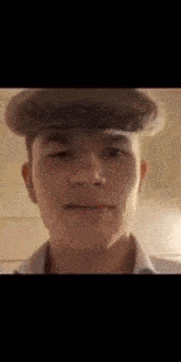 a young man wearing a hat is looking at the camera and smiling .