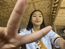 a woman wearing a lanyard that says ' do ' on it makes a peace sign