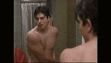 a shirtless man is standing in front of a mirror .