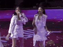 a woman singing into a microphone while another woman stands behind her