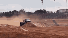 a monster truck is driving down a dirt track on a dirt road .