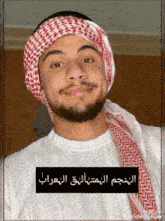 a man with a beard wearing a head scarf and a white shirt .