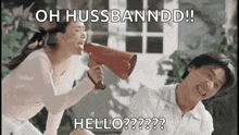 a woman is holding a megaphone in front of a man and screaming into it .