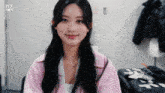 a woman in a pink jacket is smiling in front of a door that says live on