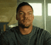 a man with a beard is wearing a gray shirt