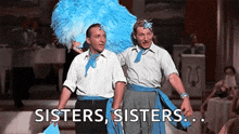 two men are standing next to each other on a stage and one of them is wearing a feathered headdress .