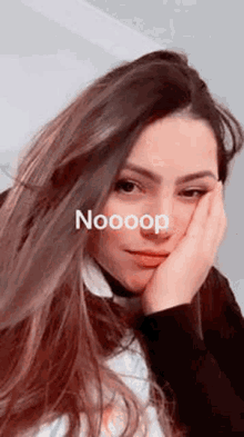 a woman with long hair is taking a selfie with her hand on her face and the words nooop written on her face .