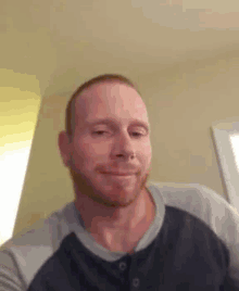 a man with a beard is smiling for the camera while wearing a blue shirt .