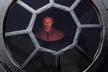 a man with a beard is looking out of a circular window