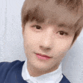 a close up of a young man 's face wearing a white shirt and a blue sweater .