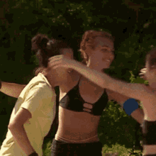 a group of women in bikinis are hugging each other in a park .