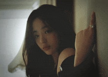 a woman leaning against a wall with a ring on her finger and a smiley face on her chest