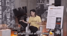 a woman wearing a yellow celine shirt is sitting in front of a sign .
