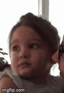 a little girl is being held by a woman and looking at the camera .