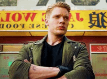 a man with his arms crossed stands in front of a sign that says " free food "