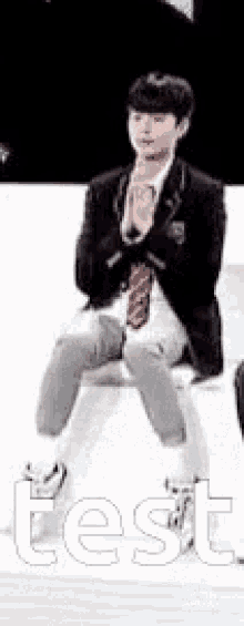 a young man in a suit and tie is sitting on a bench with his legs crossed .