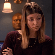 a woman in a purple shirt has her arms crossed in front of a statue