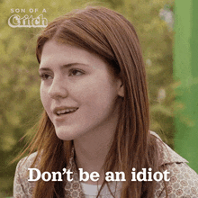 a woman with long red hair is smiling and says " don 't be an idiot "