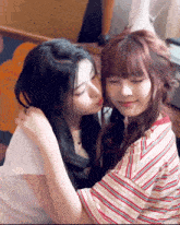 two girls hugging each other with one kissing the other on the cheek