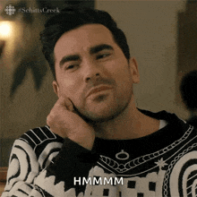a man wearing a black and white sweater says hmmm