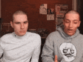 two men standing next to each other with one wearing a hoodie that says ' rage ' on it