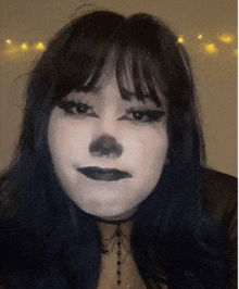 a woman with black hair and white makeup has a nose piercing