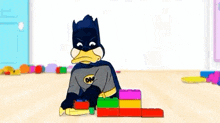 a cartoon of a duck dressed as batman playing with blocks on the floor .