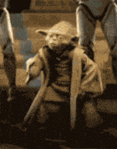 a statue of yoda from star wars is kneeling down in the dirt
