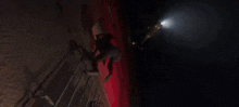 a woman is climbing up a ladder in a dark room with a light shining on her .