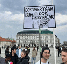a man holding a sign that says " dostum erdogan buna çok kizacak "