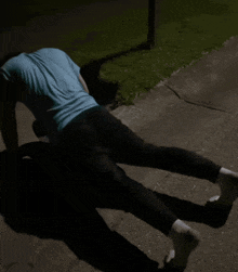 a person is doing push ups on the sidewalk at night