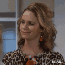 a woman wearing a leopard print shirt and earrings with a netflix logo in the corner