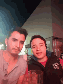 two men are posing for a picture and one of them is wearing a vest that says columbia