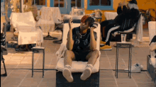 a man in a black shirt with the number 18 on it is sitting in a chair