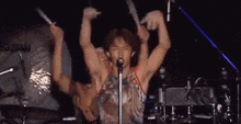 a man is singing into a microphone with his arms outstretched
