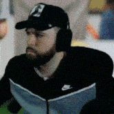 a man with a beard wearing headphones and a baseball cap