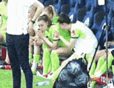 a group of female soccer players are sitting on a bench talking to each other