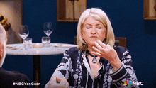 a woman is sitting at a table with a nbc logo on the bottom