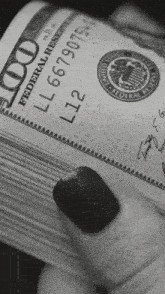 a woman holds a stack of 100 dollar bills in her hand