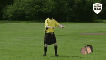 a soccer player without a head is dancing on a field with a man laying on the ground .