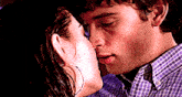 a man and a woman are kissing and the man is wearing a plaid shirt