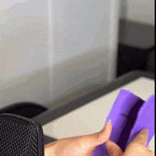 a person holding a purple object in front of a black microphone