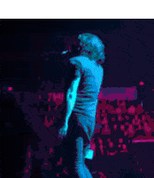 a man is standing on a stage with his arms outstretched in front of a crowd of people .