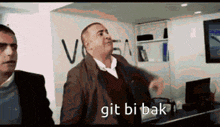 a man in a suit is standing next to another man with the words git bi bak written on the bottom
