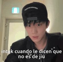 a young man wearing a black hat with the words intak cuando le dicen que no es de jiu