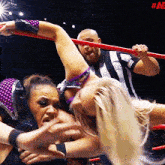 two women are wrestling in a ring with a referee behind them and the words #ae on the bottom right