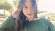 a young woman in a green sweater is making a funny face